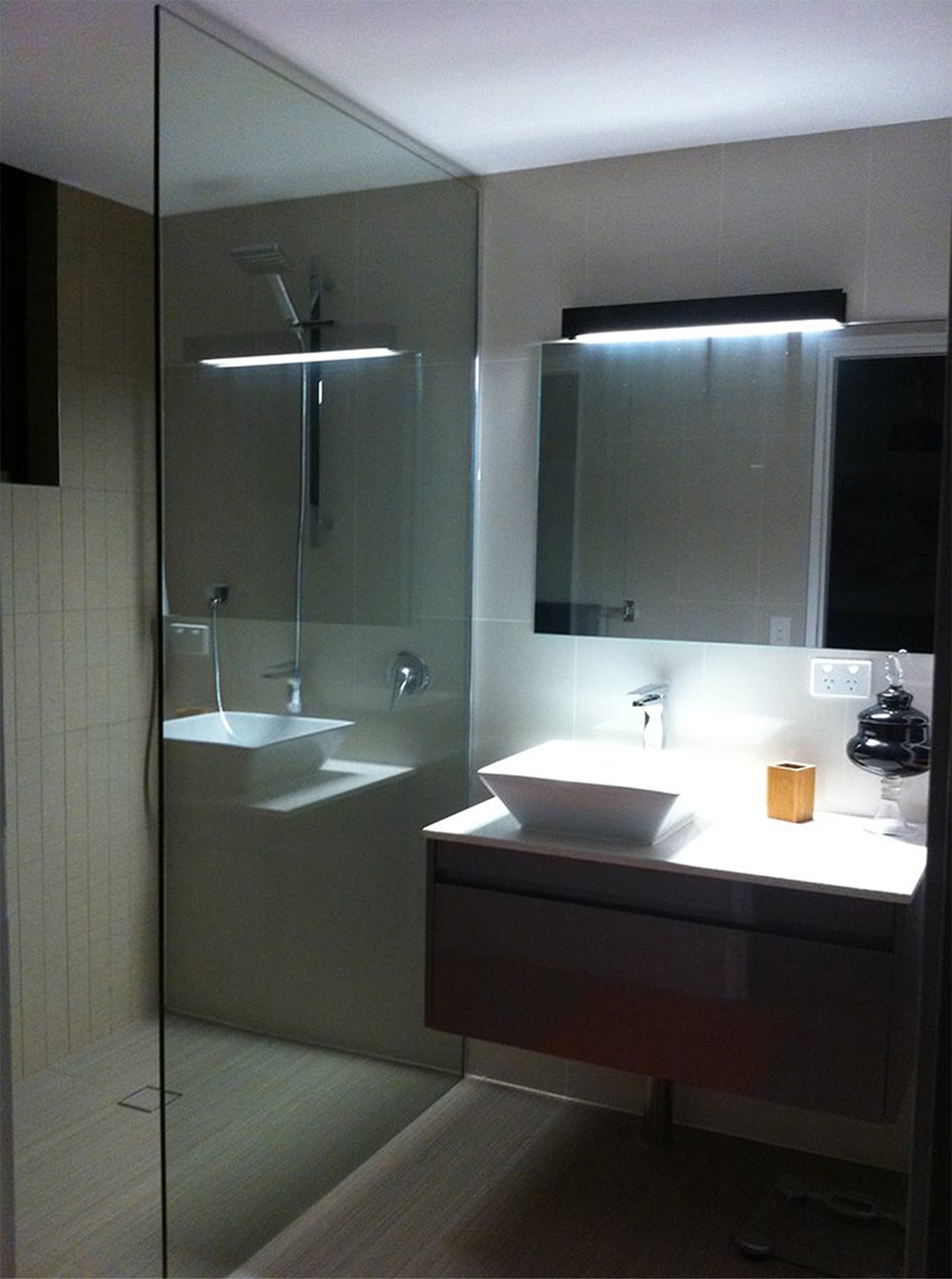 Bathroom Renovation | Before & After | Alysoun Realty After bathroom renovation: Modern, spacious bathroom with frameless shower screen, floating vanity, stylish tiles, improved lighting, and ample storage.