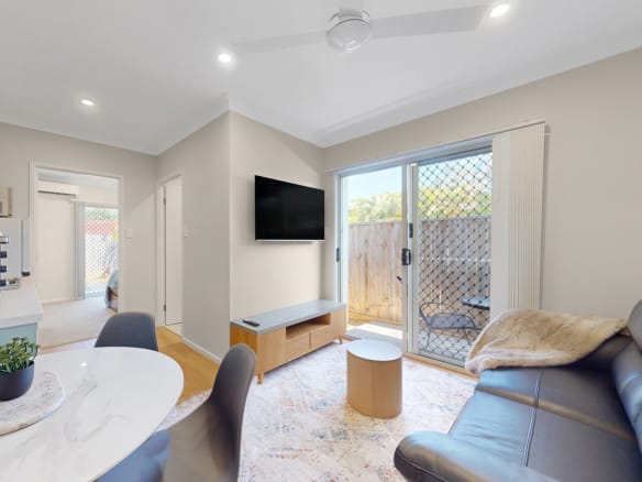 Modern rooming house studio interior with open plan living, kitchenette, bedroom access and private outdoor courtyard in Brisbane